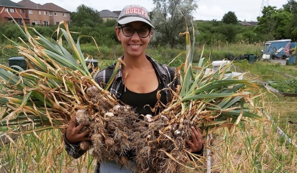 Rav Singh standing in the middle of a field holding her crops.
