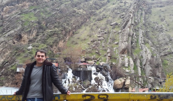 photo of Ehsan leaning against a railing with a mountainous background.