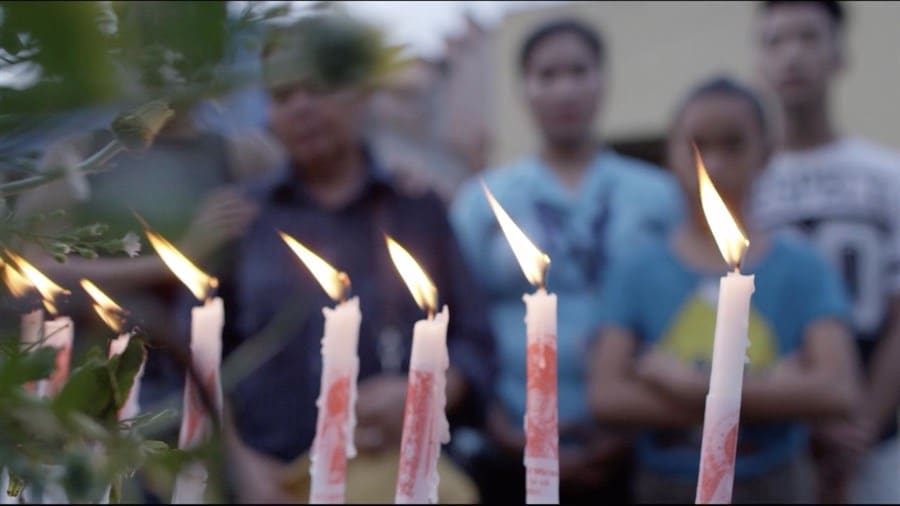 Ignited candles stand in front of a group of people in the background.