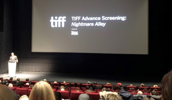 A black screen with white text on it in a movie theatre.
