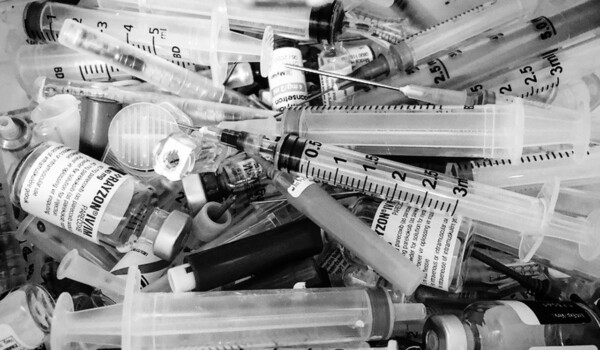 A black and white photo of a pile of syringes.