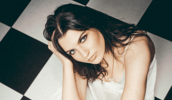 Erica Knox sitting in a white dress on a black and white tile floor