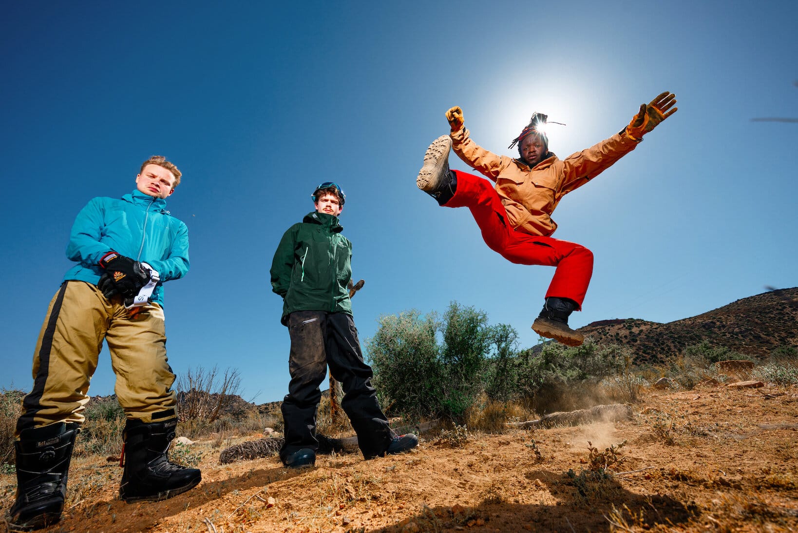 The three members of black midi are dressed in hiking gear in the desert